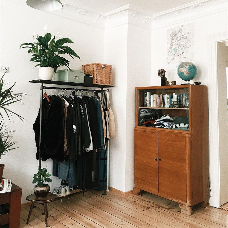 Free standing clothing rack made from dark iron pipes with dark shelf on top for plants and boxes and shoe rack