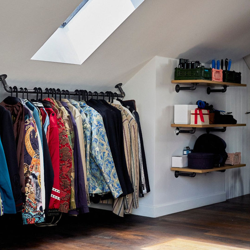 Practical sturdy clothes rail attached on slanted ceiling made from dark iron pipes