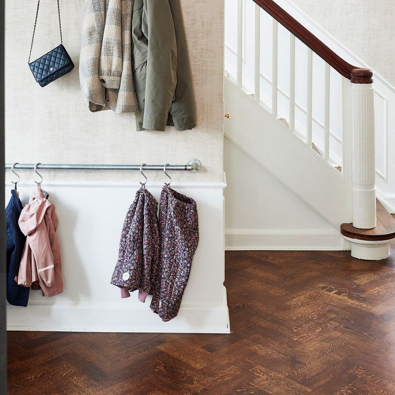 Simple clothes rail attached to wall for children´s jackets and rain pants in silver water pipes